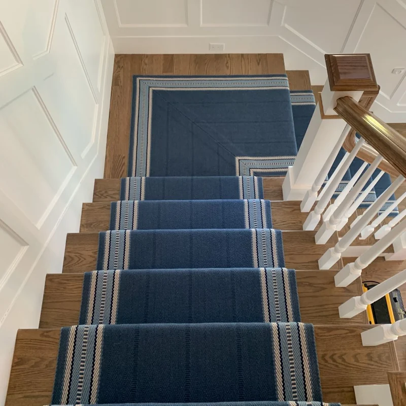 Blue striped runner on light wood stairs.